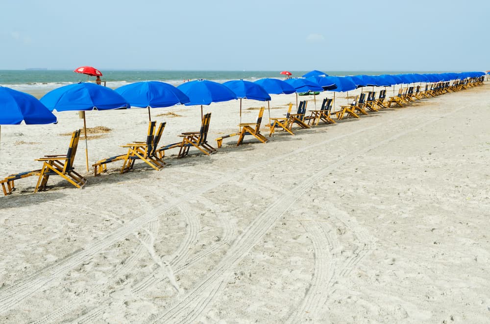 Row of beach chairs under blue umbrellas